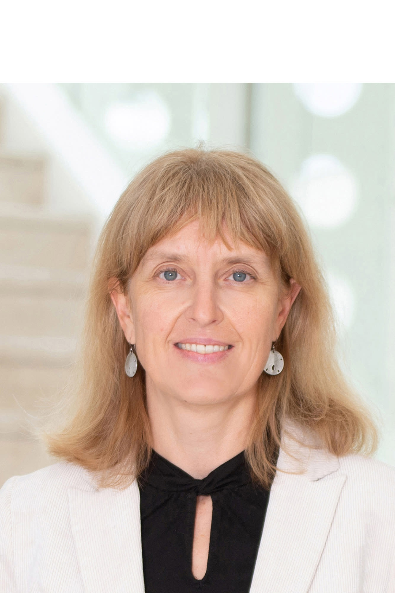Bild von Bettina Kugi in weißem Blazer.